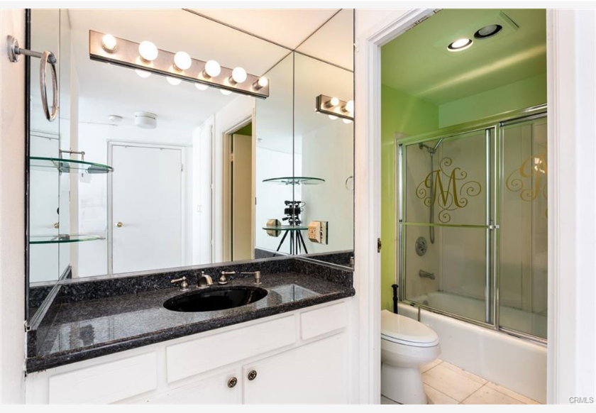 700 E Ocean Blvd #2308 — bathroom with vanity, mirrored wall, and glass shower enclosure