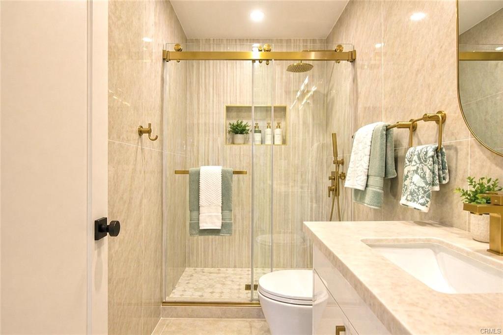 9142 Parliament Ave — primary bathroom with gold fixtures and frameless glass shower