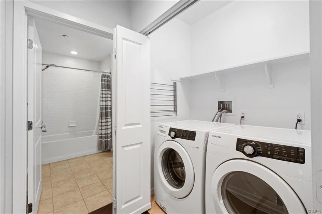21 Gramercy #202 — interior laundry area with washer, dryer, and storage