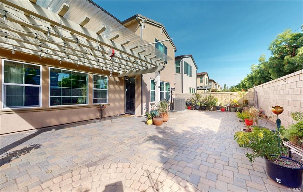 12954 Dahlia St — private backyard with pavers, pergola, and mature landscaping
