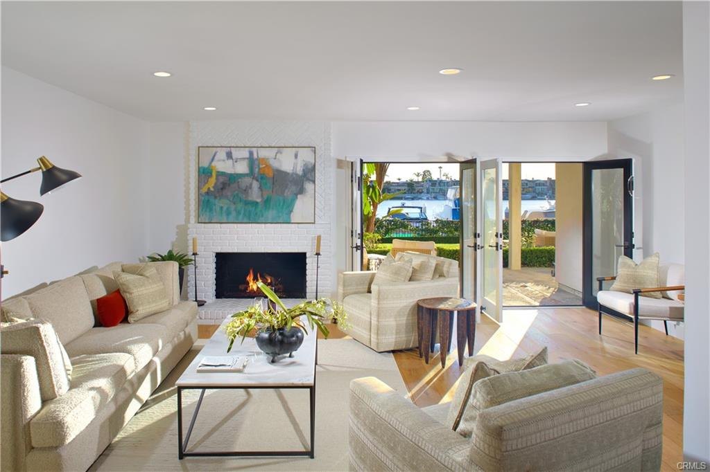 2572 Bayshore Dr — living room with white brick fireplace and French doors to the bay
